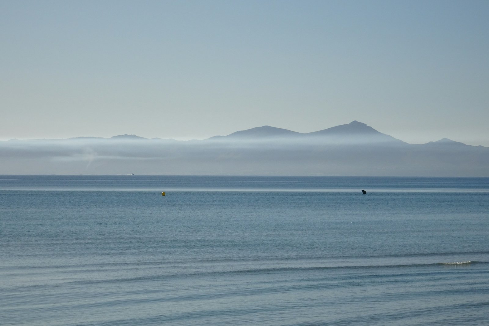 Ruhiges Meer vor einer markanten Bergsilhouette